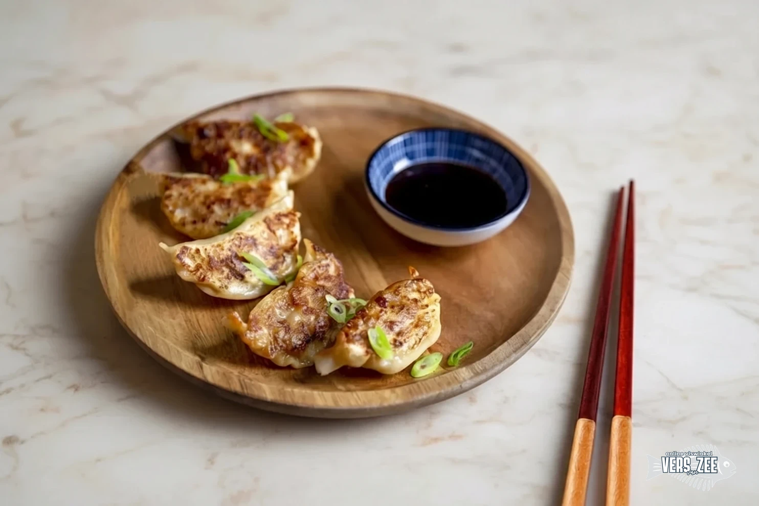 Vier gebakken gyoza dumplings met bosui op een rond houten bord, geserveerd met sojasaus en eetstokjes op een lichte marmeren ondergrond.